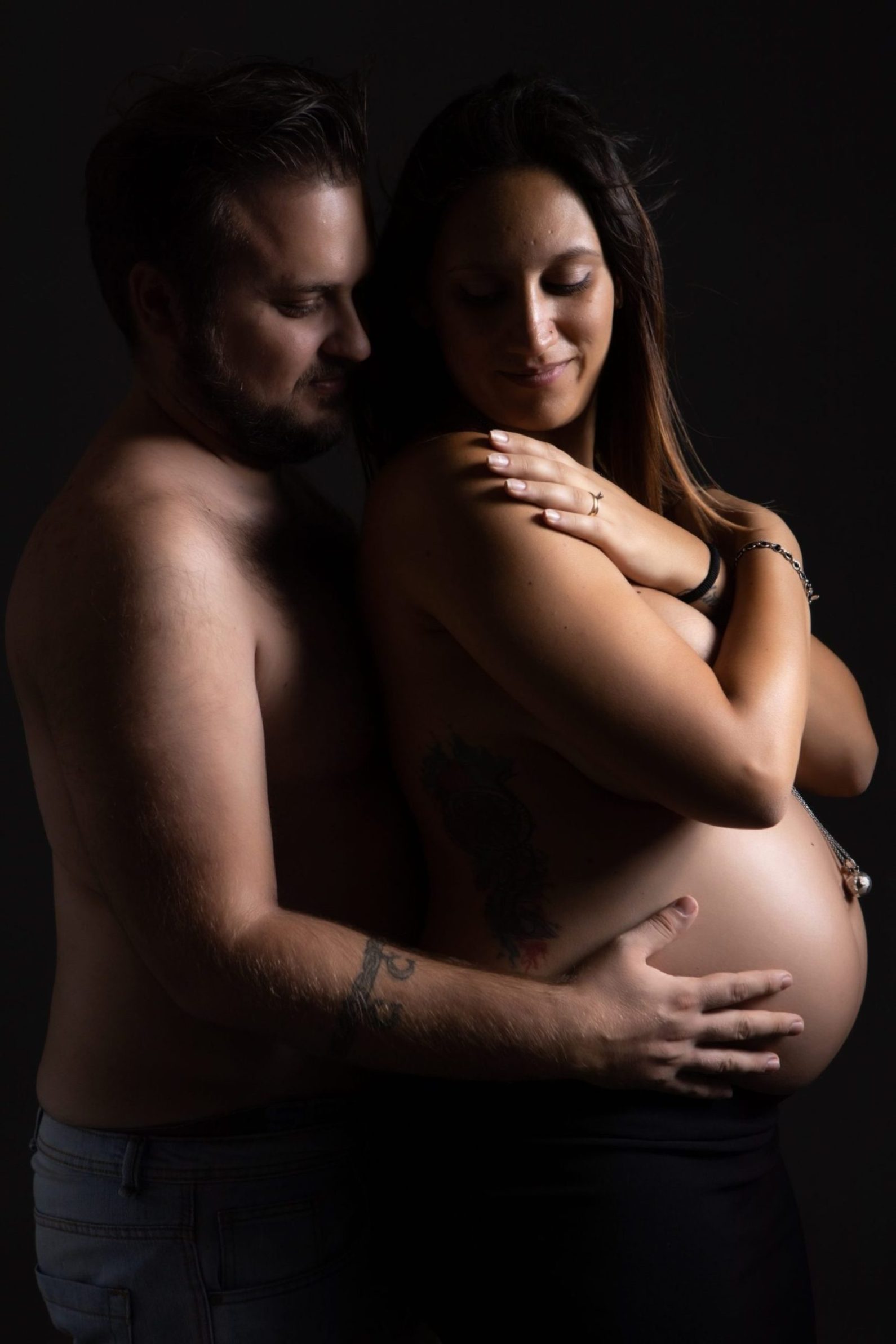 fotografia pancia donna incinta abbraccio coppia felice gravidanza maternità dolce attesa futura famiglia coppia abbraccio contrasti di luci servizio fotografico maternità