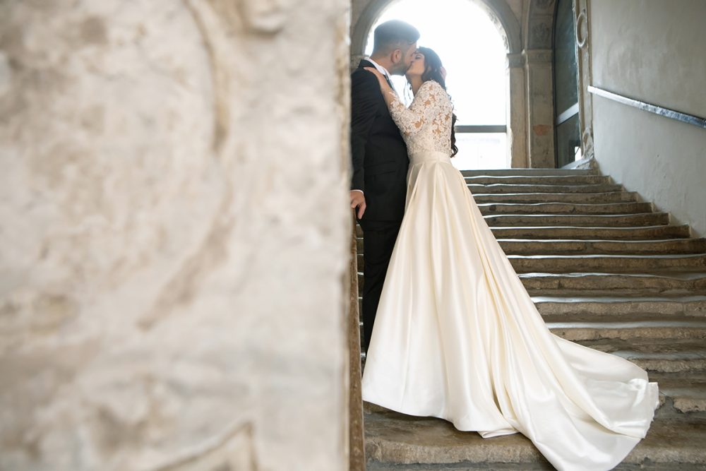 servizio fotografico matrimonio carpi fotografo cerimonie foto sulle scale bacio romantico strascico abito da sposa bianco 