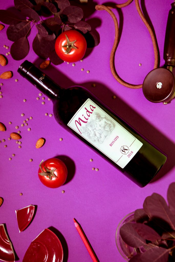 fotografia emozionale su sfondo viola bottiglia di vino con oggetti coordinati still life