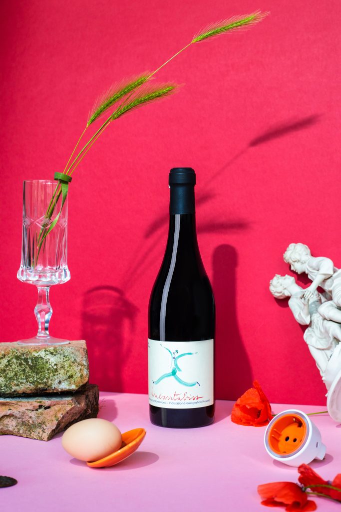 fotografia emozionale su sfondo rosso bottiglia di vino con oggetti coordinati still life