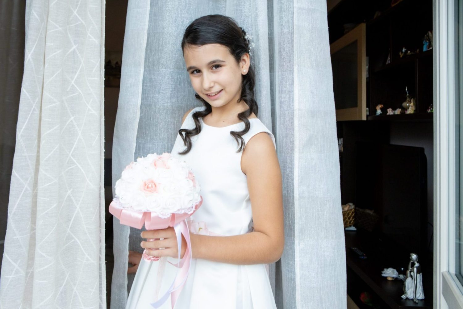 bambina comunione vestito bianco cintura fiori rosa sorriso evento cerimonia acconciatura boccoli bouquet di fiori vestito da cerimonia comunione cresima fotografo
