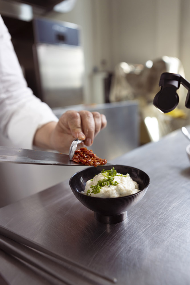 Chef rifinisce un piatto durante un servizio di food styling in cucina professionale