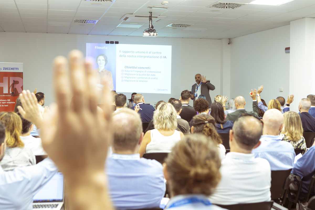 Platea durante una conferenza aziendale con relatore e slide proiettata