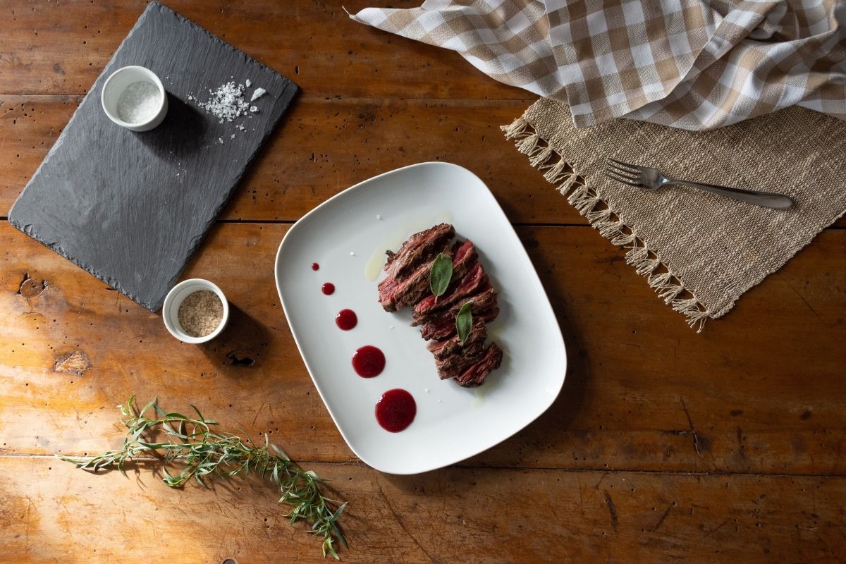 Piatto di carne con salsa ai frutti rossi in un servizio di fotografia food & wine
